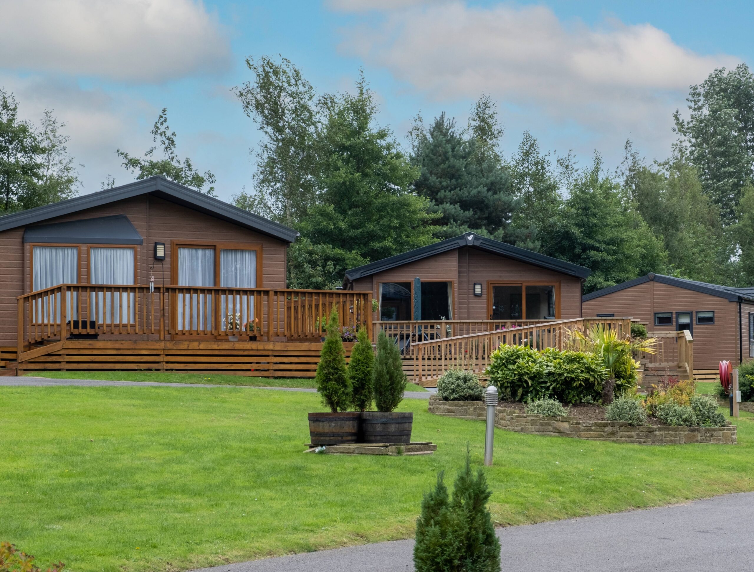 Three wooden homes overlooking a lush patch of green grass