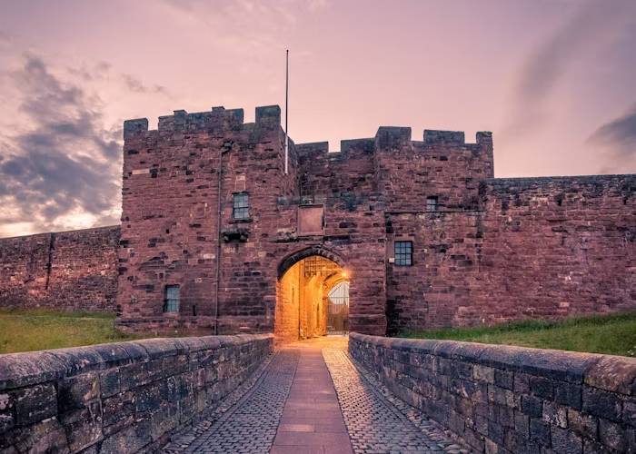 Image of a majestic castle gateway, featuring detailed architecture and vibrant foliage framing the entrance.