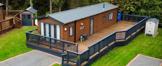 A birds eye view of a dark brown wooden holiday home with an expansive deck