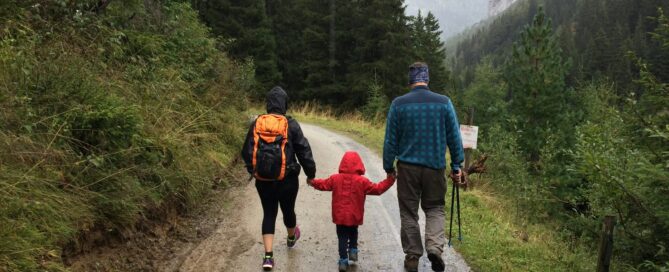 family of three walking in forest